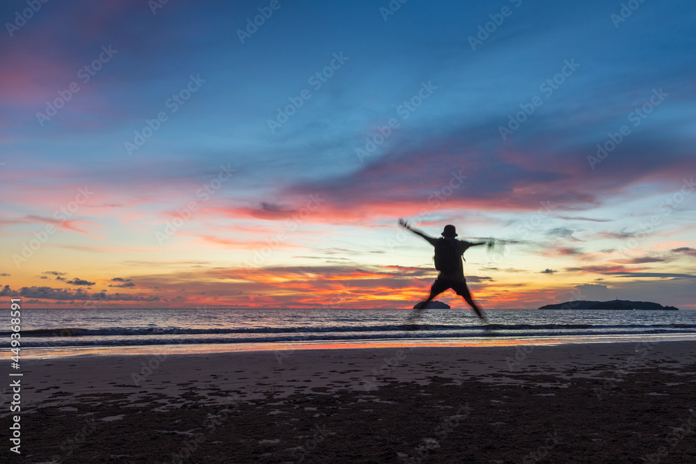 A happy man jump during beautiful twilight sunset on beach