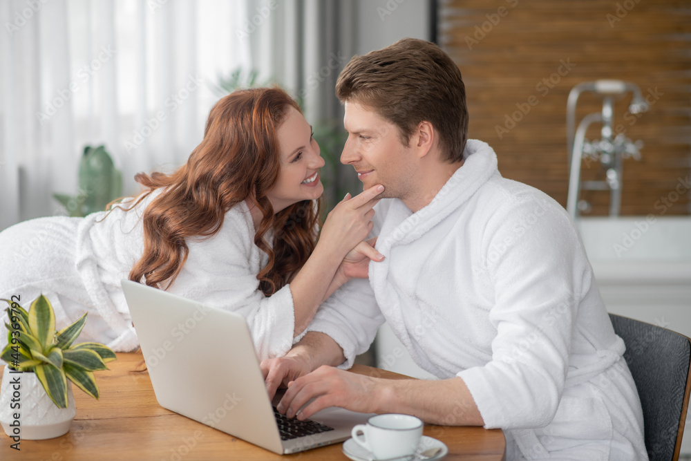 Ginger woman in a white bathrobe and her husband looking happy and in love Ginger woman in a white bathrobe and her husband looking happy and in love