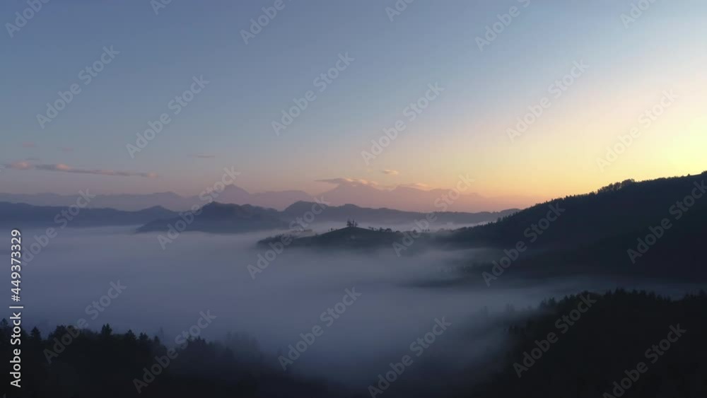 Aerial landscape of mountain hills covered in fog and Saint Thomas church, Slovenia on sunrise Aerial landscape of mountain hills covered in fog and Saint Thomas church, Slovenia on sunrise