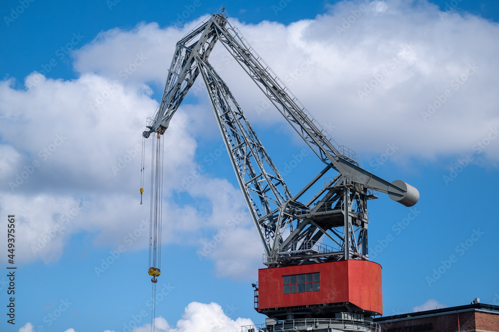Closeup of an old decomissioned harbor crane against vivid sky.