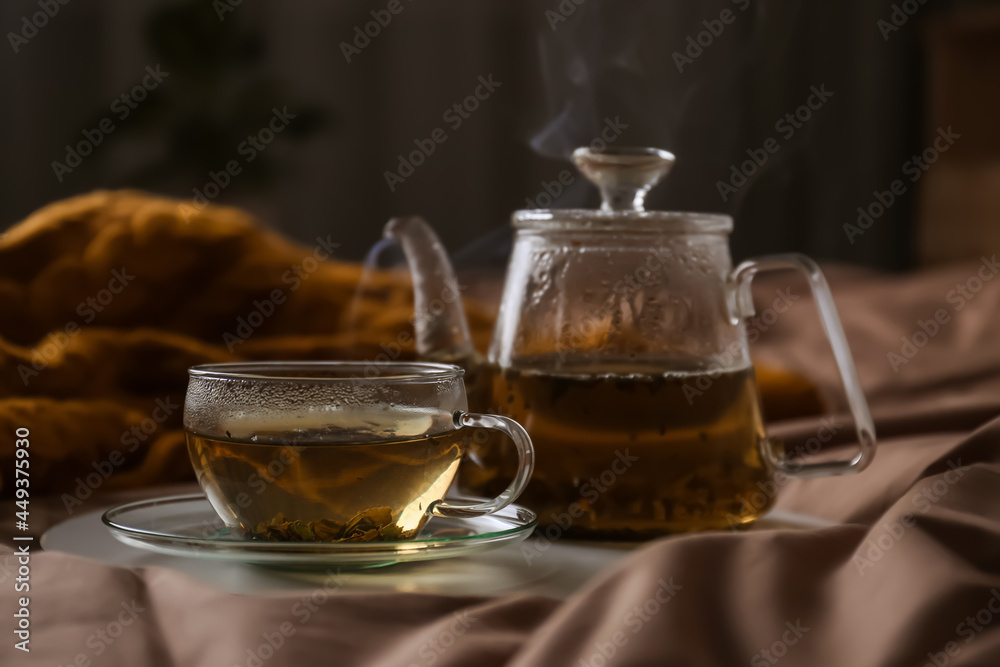 Tray with cup of hot tea and teapot on bed Tray with cup of hot tea and teapot on bed