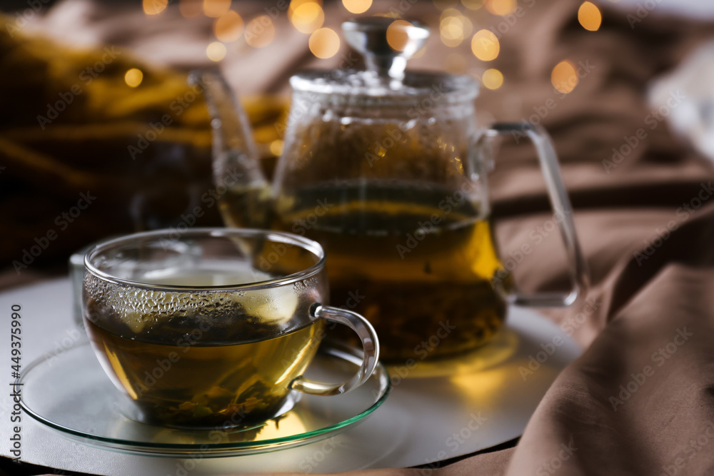 Tray with cup of hot tea and teapot on bed Tray with cup of hot tea and teapot on bed