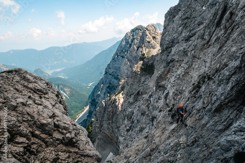 Hiker climbing Mount Prisojnik in Slovenia under a bright sky on a sunny day photo