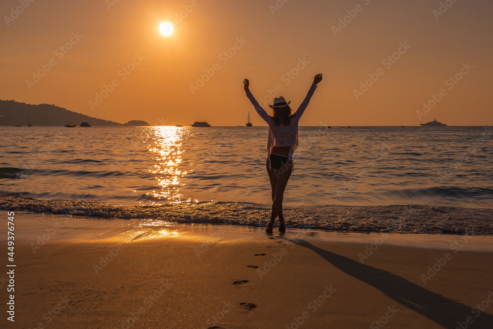A girl in the setting sun on Patong beach on Phuket island, Thailand