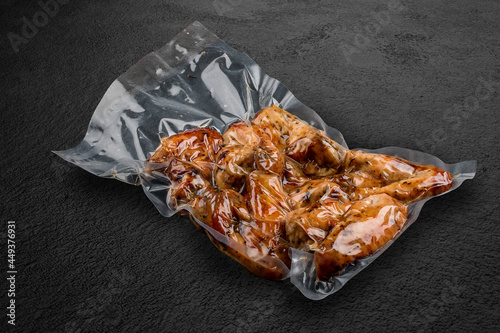 Vacuum-packed grilled meat, on a dark background, chicken wings. Ready to eat.