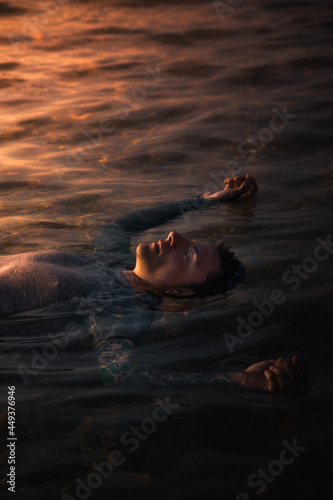 man floating on water at sunset