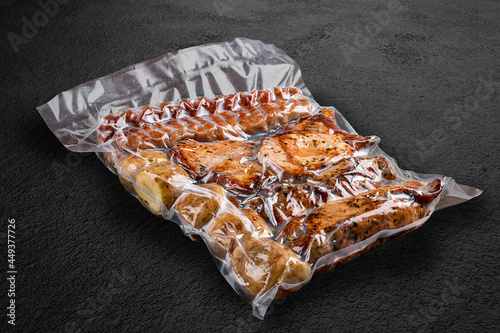 Vacuum-packed grilled meat, on a dark background. Set of different types of meat and potatoes. Ready to eat.
