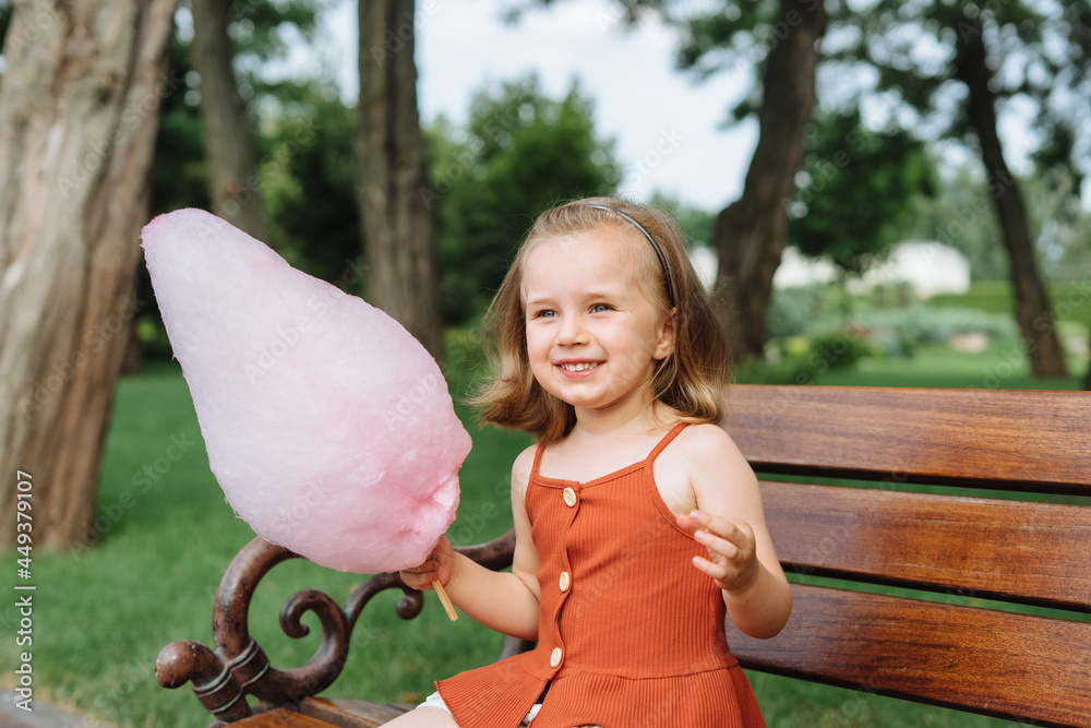 Beautiful little girl eating pink cotton candy in the park. Stock Photo