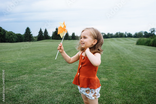 Happy little child with pinwheel playing outdoors