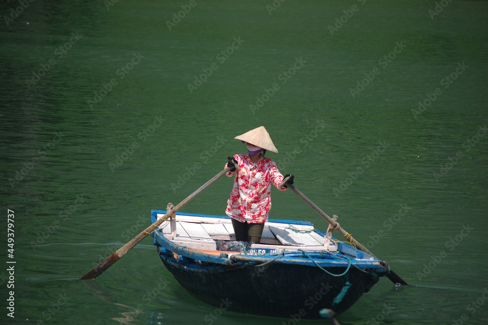 Vietnamese women people rowing retro vintage boat for bring foreign travelers travel visit cave and respect small shrine in Halong or Ha Long Bay UNESCO World Natural Heritage Site in Hanoi, Vietnam