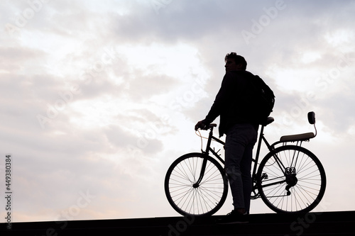 silhouette of a young man holding a bike