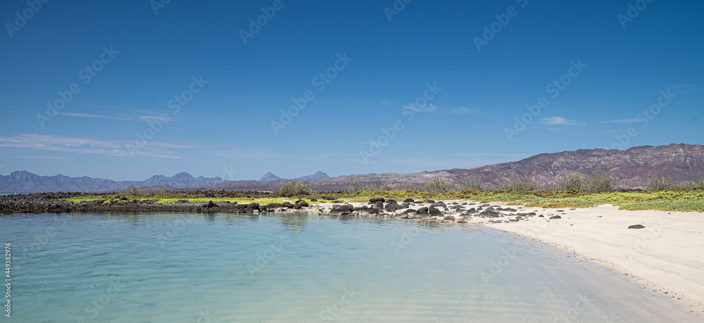 Panoramic view of white sand beach under a blue summer sky with mountains and crystal clear water at Isla Coronado or Coronado island in Loreto Baja California Sur. MEXICO