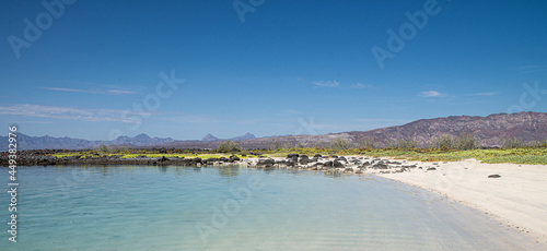 Panoramic view of white sand beach under a blue summer sky with mountains and crystal clear water at Isla Coronado or Coronado island in Loreto Baja California Sur. MEXICO