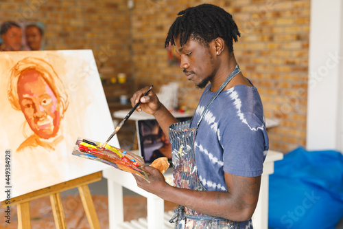 African american male painter at work painting portrait on canvas in art studio photo