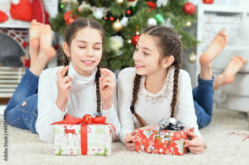 Cute little girls with presents near decorated Christmas tree