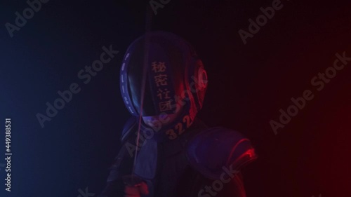 Cyberpunk future concept. Bionic cyborg police officer with short samurai sword stands in dark with smoke, fume. Halfman robot looks at camera. Futuristic science fiction scene. Red blue light blinks photo
