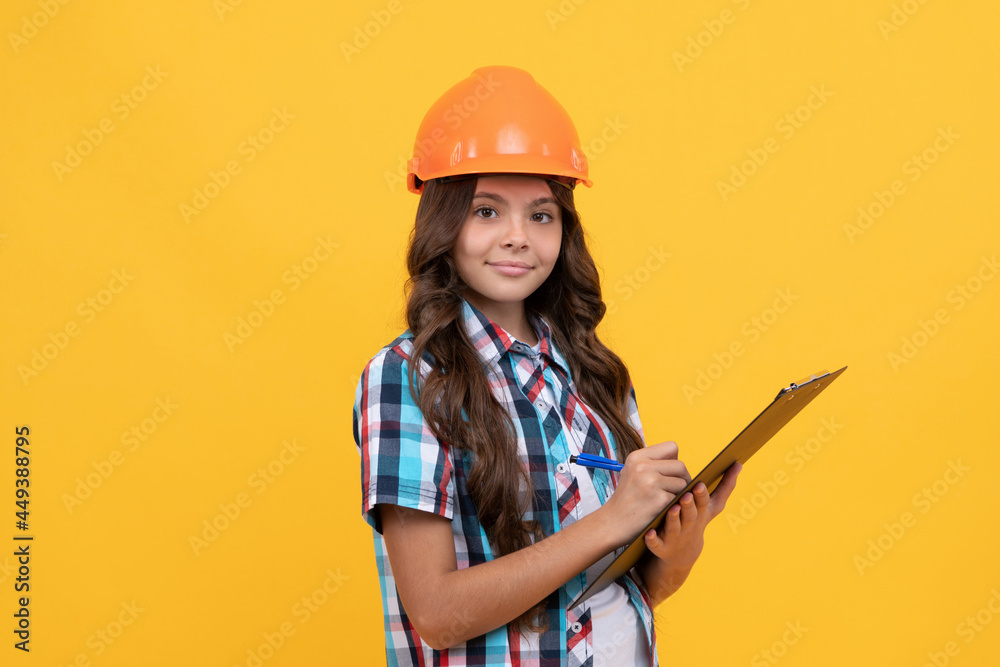 smiling child in construction helmet making notes in clipboard, document work smiling child in construction helmet making notes in clipboard, document work