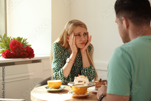 Young woman getting bored during first date with man in cafe photo