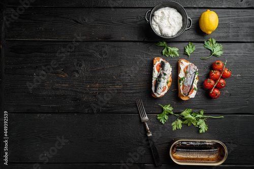 Sandwich with smoked fish, on black wooden table background, top view flat lay, with copy space for text