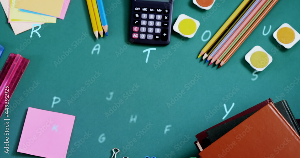 Digital composition of multiple alphabets floating against school stationary equipment on green surf Digital composition of multiple alphabets floating against school stationary equipment on green surf