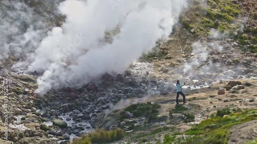 Hiking and eco tourism lady shoots video near huge geyser Explore travel with hike hikes in valley. Experience eco tourism at geyser with landscape views. Join our tourism adventure in kamchatka,