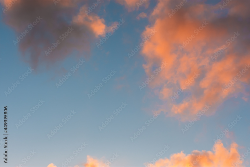 Clouds sunset background. Pastel delicate shades of the sky. Beautiful clouds for an airy light summer design. The concept of lightness, weightlessness, romance, tenderness. The sky is in orange light