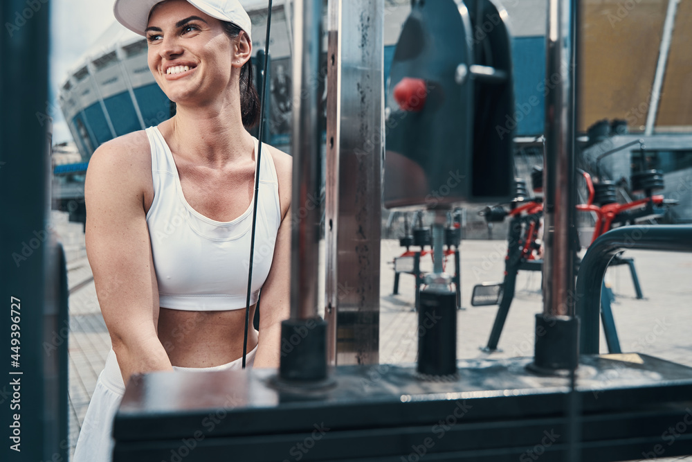 Obraz premium Satisfied athletic female smiling during arm muscles exercise