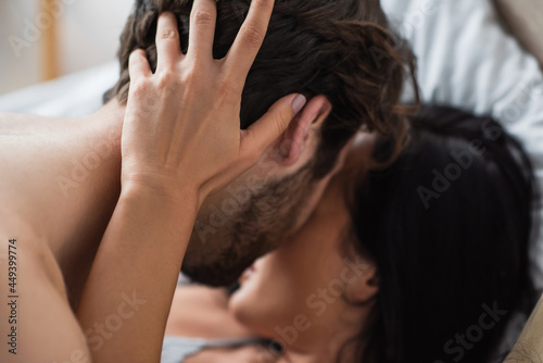 blurred woman making out with shirtless man in bedroom