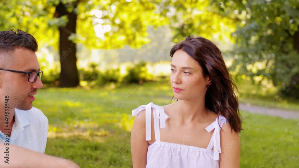 leisure and people concept - happy couple talking at summer park leisure and people concept - happy couple talking at summer park