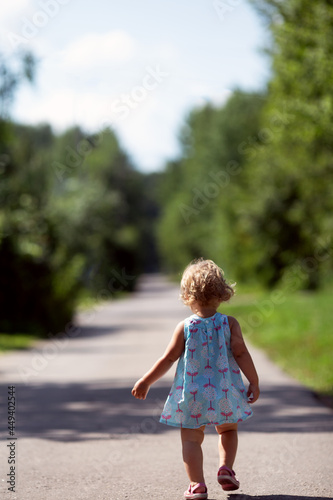 Little girl walking street countryside. Back view. Carefree childhood