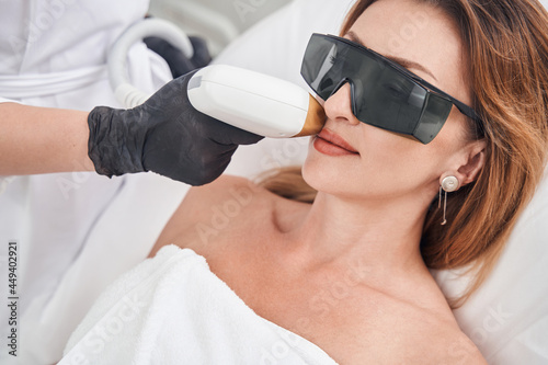 Relaxed pretty woman during face laser epilation photo