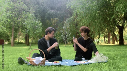 A guy takes pictures on the phone of another guy in nature in the summer