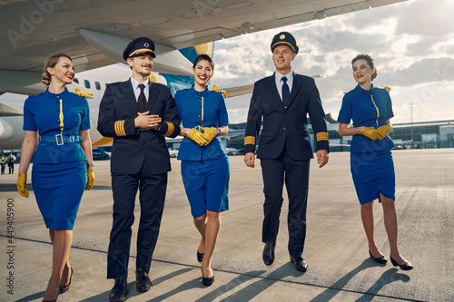 Happy aircrew in uniforms going along the runway