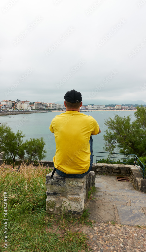 man from his back overlooking the sea enjoying a cloudy autumn day