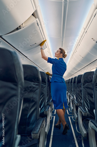 Stewardess in leather gloves shutting an aircraft stowage bin