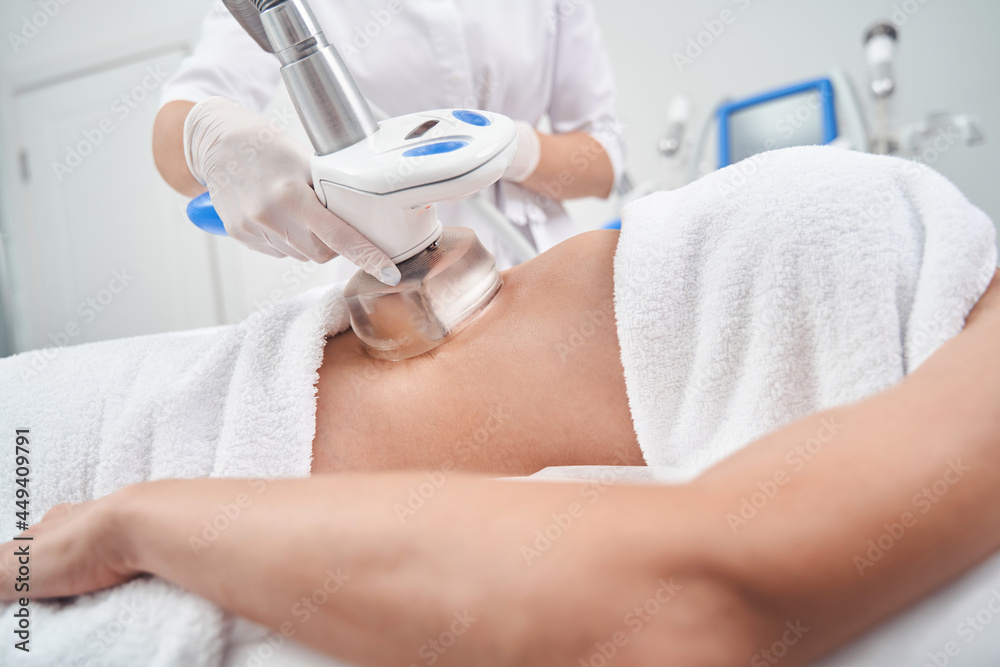 Woman doing anti-cellulite massage for abdomen in studio Woman doing anti-cellulite massage for abdomen in studio