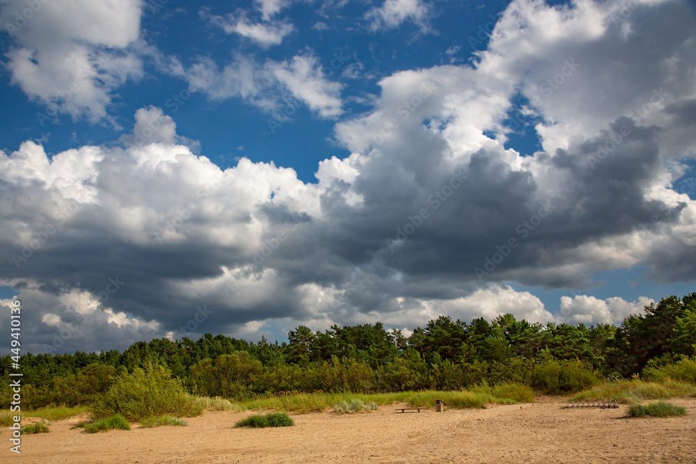 Cumulus clouds over wild sandy coast of the Baltic Sea in Vecaki, Latvia