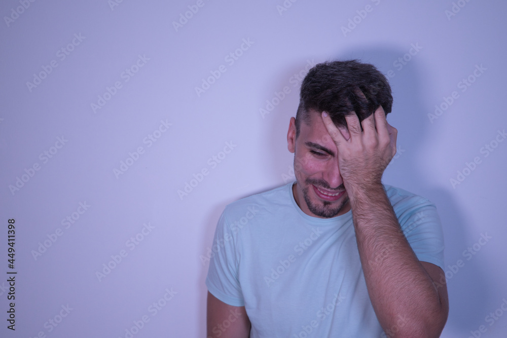 Young Hispanic male with hand on head and wincing in pain on white background. Young Hispanic male with hand on head and wincing in pain on white background.