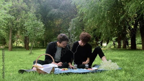 Two young guys in love listen to music in nature in the summer