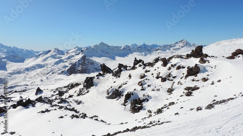  View of snow-capped mountains and dark granite stones. Snow capped mountains, blue sky on a clear day. 