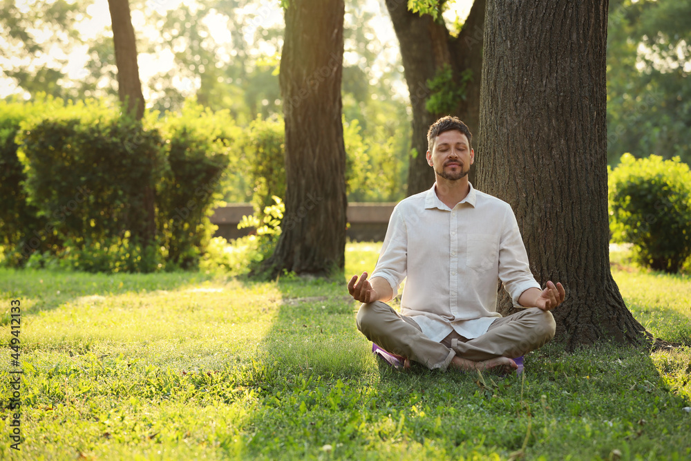 Man meditating in park on sunny summer day. Space for text Man meditating in park on sunny summer day. Space for text