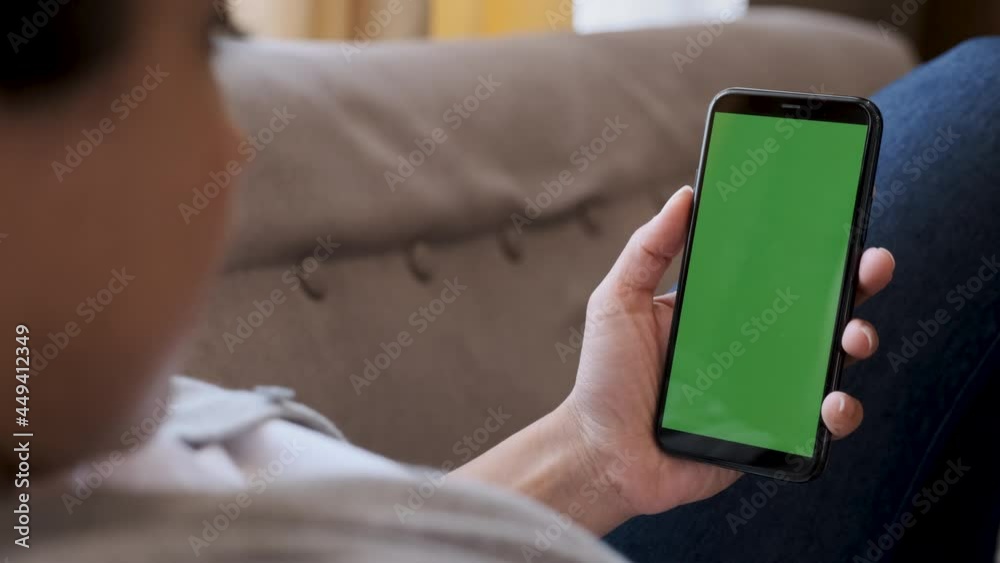 Woman using smartphone watching green screen on mobile phone, online enjoying reading social media at home close up hands Woman using smartphone watching green screen on mobile phone, online enjoying reading social media at home close up hands