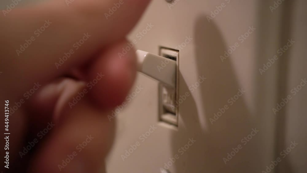 Person turns light switch on and off. Close up of finger.
