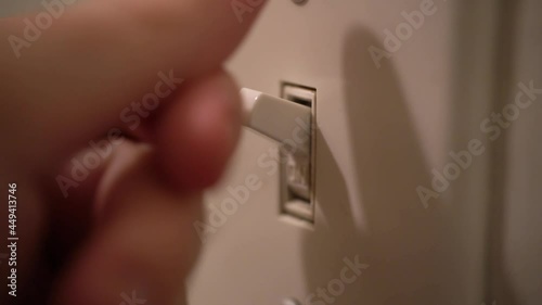 Person turns light switch on and off. Close up of finger.