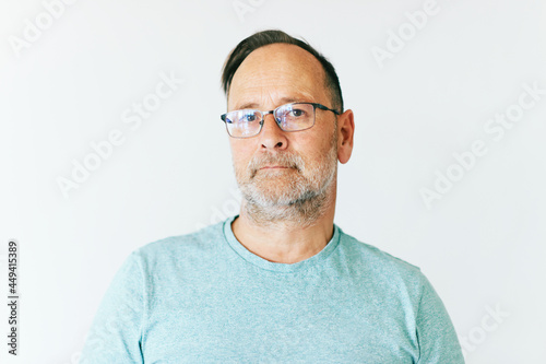 Close up portrait of middle age man wearing glasses and turquoise t-shirt, white background © annanahabed