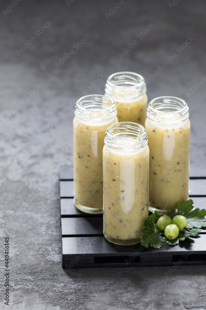 Summer drink, gooseberry smoothie in a tall glass bottle with a straw on a dark gray background Summer drink, gooseberry smoothie in a tall glass bottle with a straw on a dark gray background