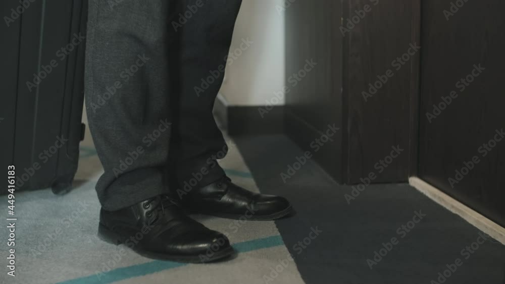 Low-section shot of unrecognizable businessman with baggage walking into hotel room opening door with key card Low-section shot of unrecognizable businessman with baggage walking into hotel room opening door with key card