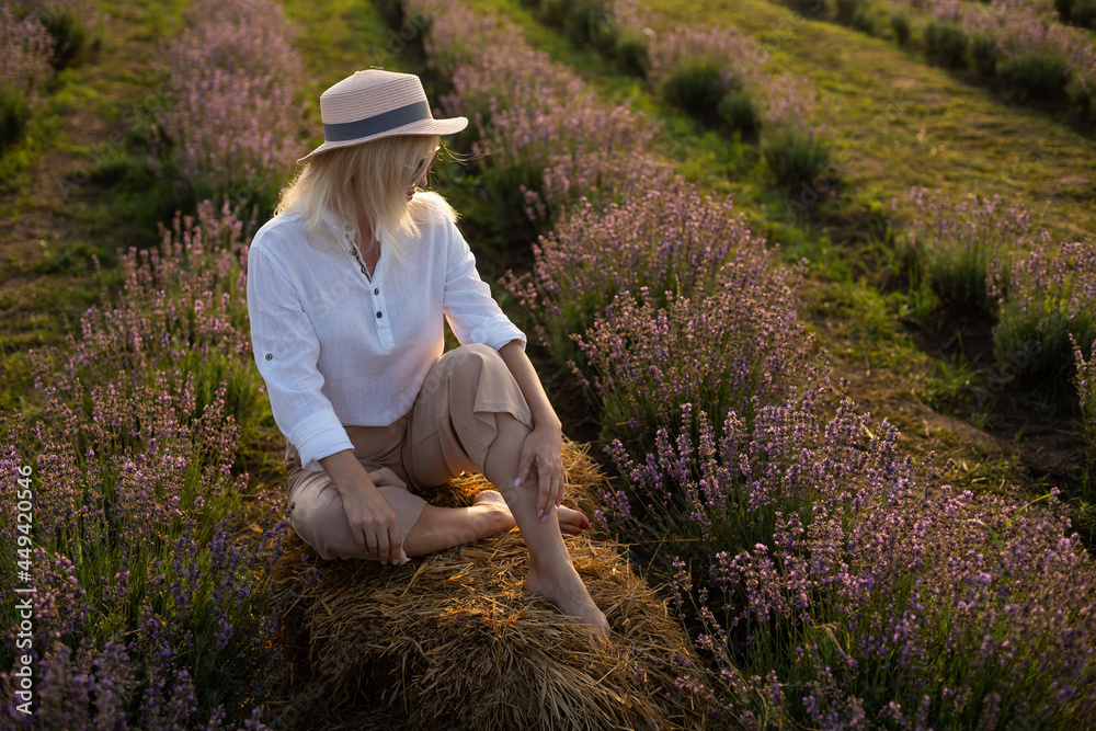 Young woman standing on a lavender field with sunrise on the background Young woman standing on a lavender field with sunrise on the background