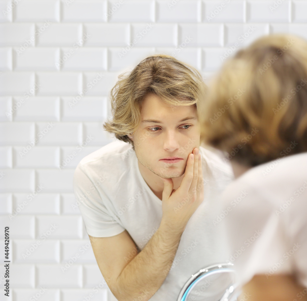 young man looking in the mirror,combing his hair,looking at problems on face. young man looking in the mirror,combing his hair,looking at problems on face.