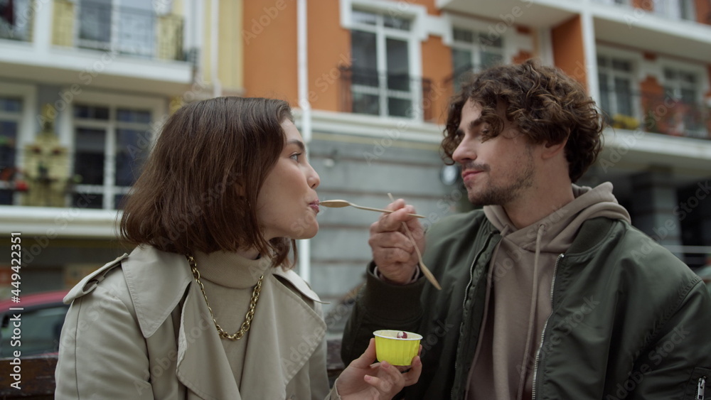 Cheerful couple eating ice cream outdoor. Joyful pair kissing on city street. Cheerful couple eating ice cream outdoor. Joyful pair kissing on city street.
